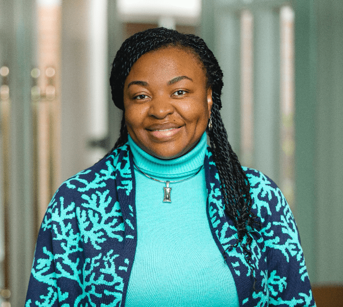 A woman with long braids wearing a blue sweater.