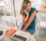 A woman sitting at a table talking on the phone.